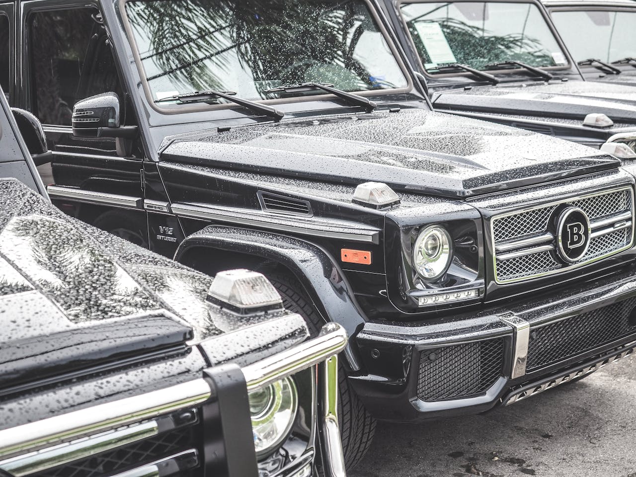 home-hero Close-up of luxurious black SUVs with raindrops, showcasing luxury vehicles under rainy conditions.